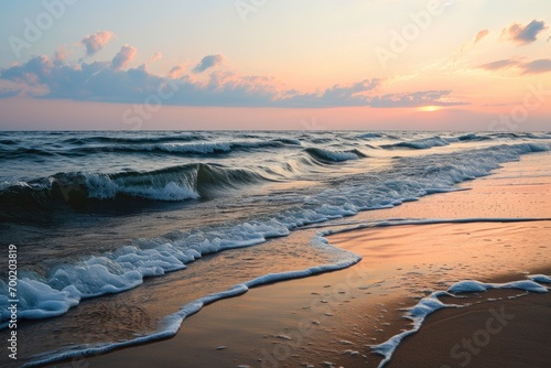 Sunset over a serene beach with smooth waves and pastel sky.