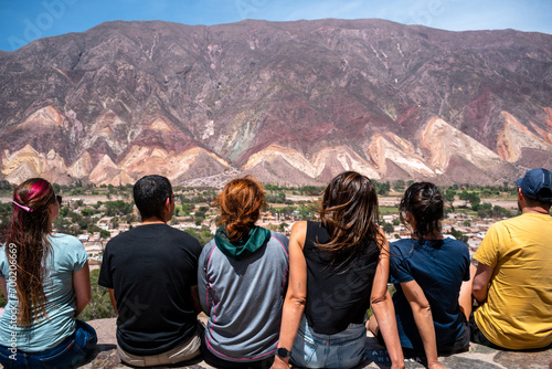 Grupo de amigos sentados en el mirador de Maimará admirando los cerros coloridos photo