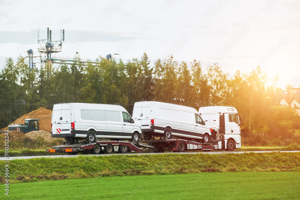 Obraz premium Roadside assistance transports a car with a breakdown on the road. Rollback tow truck. A tow truck delivers a failed vehicle. Roadside assistance helps a driver in trouble.
