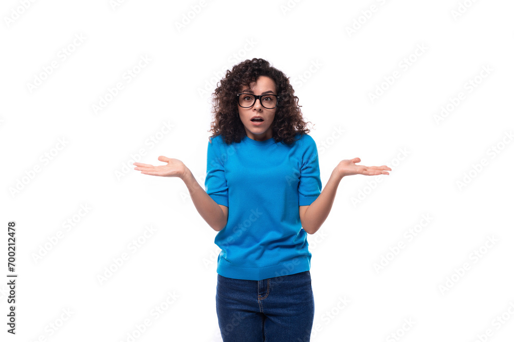 a young woman with curls dressed in a blue T-shirt shrugs her shoulders in confusion a young woman with curls dressed in a blue T-shirt shrugs her shoulders in confusion
