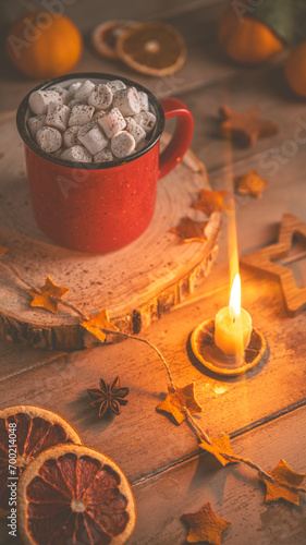 Cute cozy winter composition. red mug, marshmallows, oranges and Christmas lights.