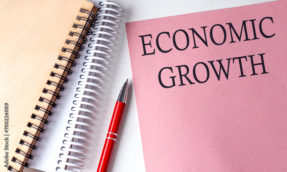 ECONOMIC GROWTH word on the pink paper with office tools on white background ECONOMIC GROWTH word on the pink paper with office tools on white background