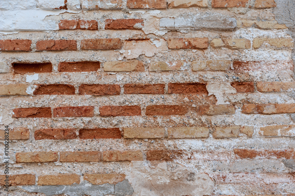 Fototapeta premium Weathered Red Brick Wall with Peeling Plaster