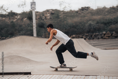 Photos young man with white t-shirt skating in a skate park