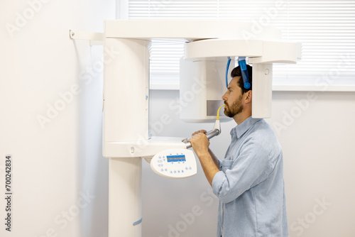 Male patient during an X-ray of the jaw with a modern scanner in clinic. Stomatological department and diagnostics concept photo