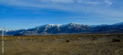 Landscape of wet clay desert in winter against the backdrop of snow-capped mountains in the Death Valley area photo