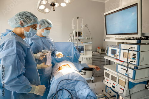 Two surgeons performs minimally invasive procedure with endoscopes, looking on monitor in operating room. Concept of endoscopic-computer assisted treatment