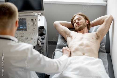 Young guy during an ultrasound diagnosis of the lower abdomen. The concept of ultrasound diagnostics and men's health photo