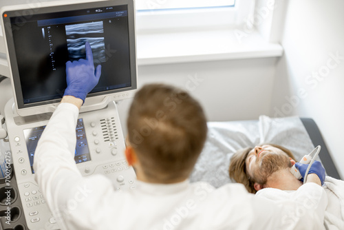 Young guy during an ultrasound diagnosis of the carotid artery. Concept of ultrasound diagnostics and men's health. Idea of examination of cardiovascular diseases photo