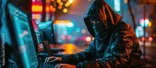 Hacker with mask and balaclava stealing data from computer.