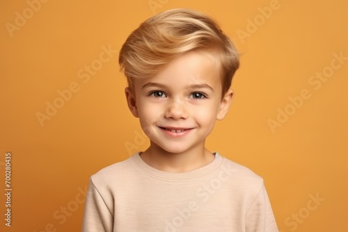cute little boy with blond hair and smiling at camera over orange background