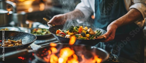 Caucasian chef stir-frying vegetables for Kung Pao Chicken. photo