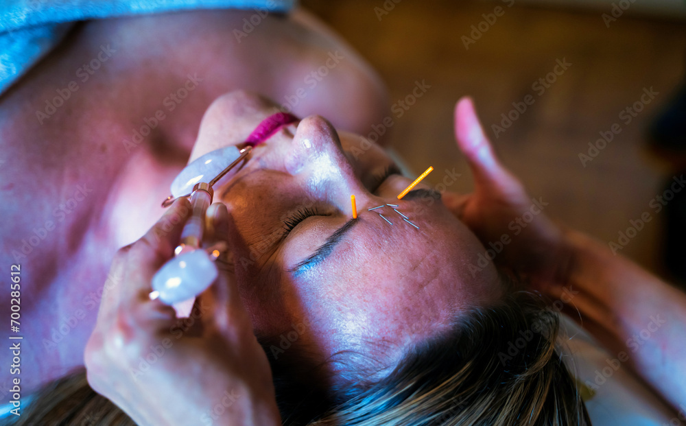 A woman undergoing acupuncture treatment on face using Jade facial massager, an item for cosmetic procedures