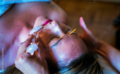Obraz na płótnie A woman undergoing acupuncture treatment on face using Jade facial massager, an item for cosmetic procedures w salonie