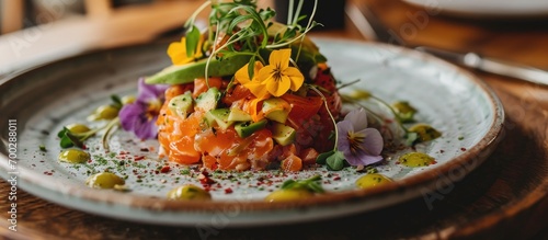 Delicious salmon tartare topped with avocado and served with flowers photo