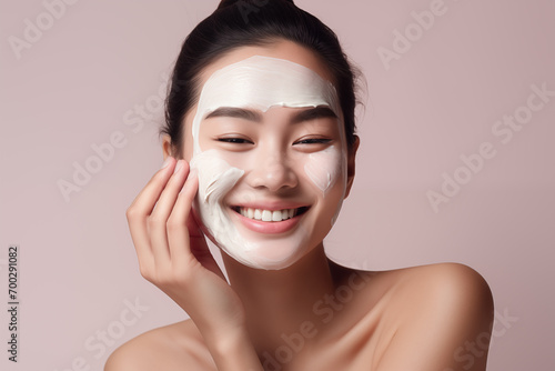 Beautiful happy smiling Asian woman applying skin care cream on her face photo