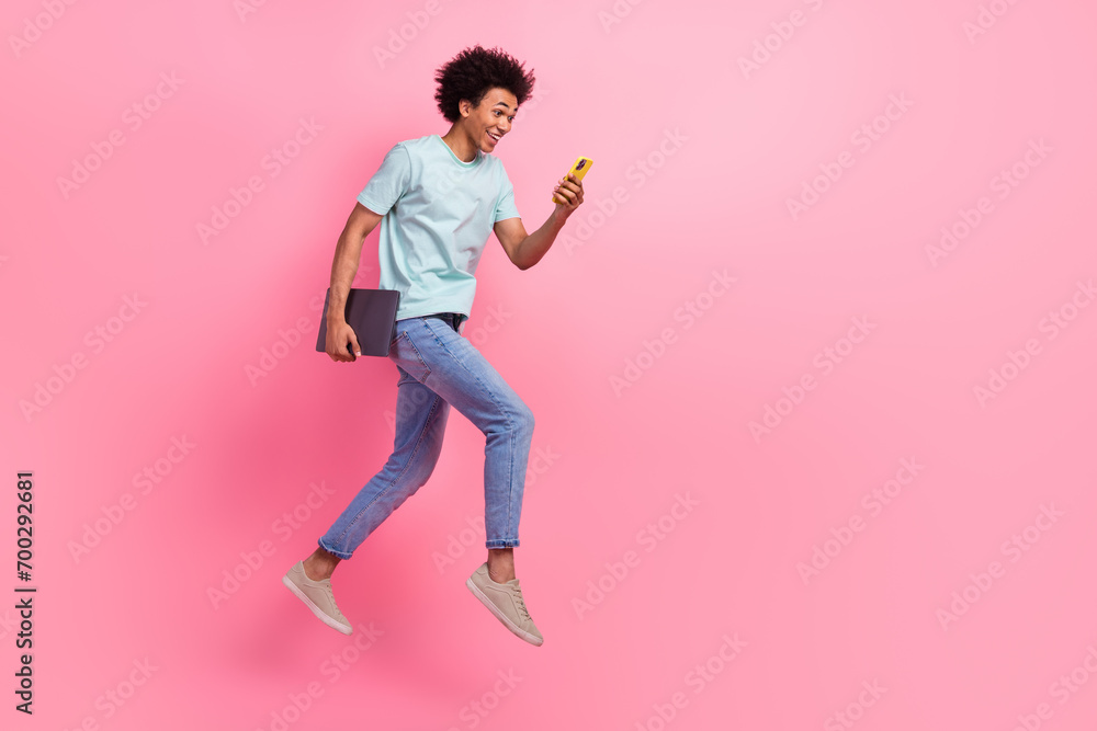 Full size photo of nice young guy running fast hold device netbook wear trendy blue outfit isolated on pink color background Full size photo of nice young guy running fast hold device netbook wear trendy blue outfit isolated on pink color background