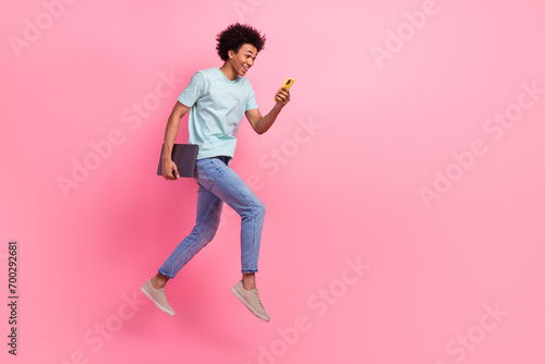 Full size photo of nice young guy running fast hold device netbook wear trendy blue outfit isolated on pink color background