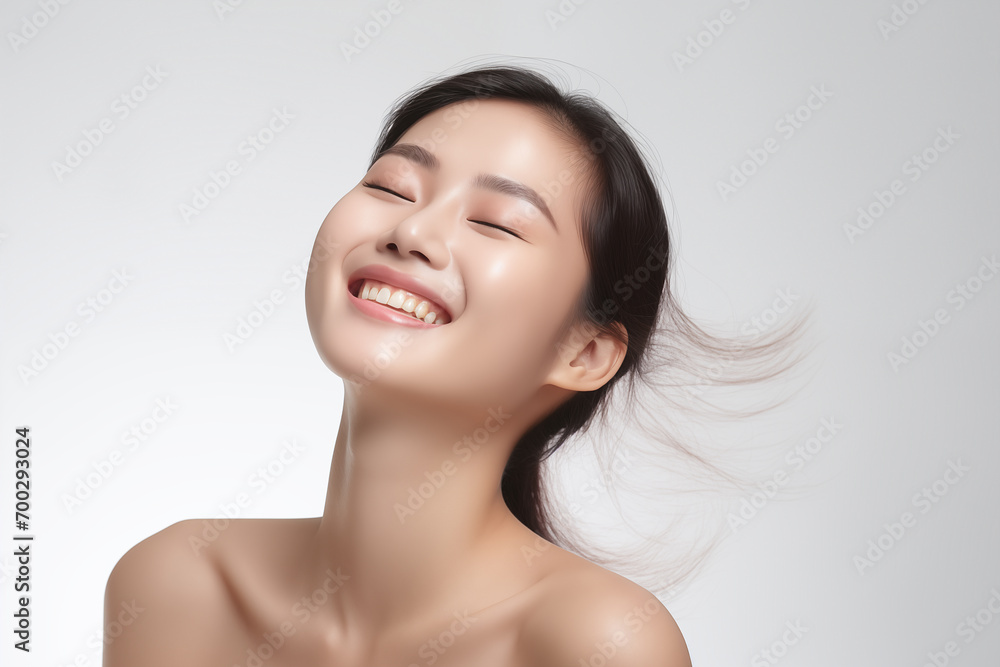 Beautiful laughing young Asian woman takes care of her skin, posing over grey background Beautiful laughing young Asian woman takes care of her skin, posing over grey background