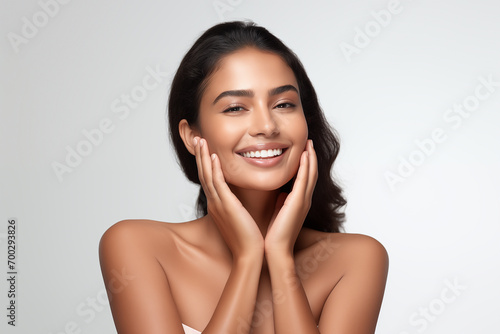Beautiful happy young Indian woman touching her face caring for facial skin. Skincare concept