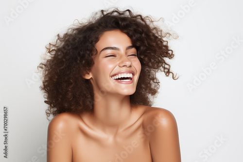 Beautiful happy Latin American woman takes care of her skin, posing over grey background