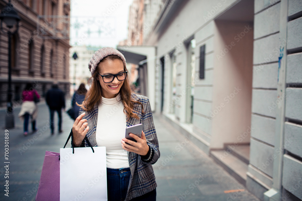 Young stylish woman using smartphone while shopping in city