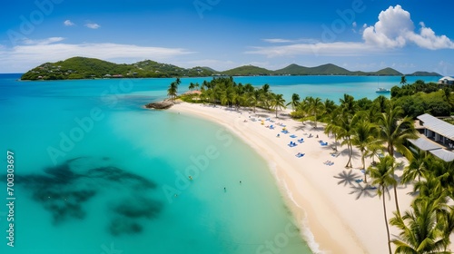 Aerial view of beautiful tropical beach with white sand, turquoise water, palm trees and blue sky.