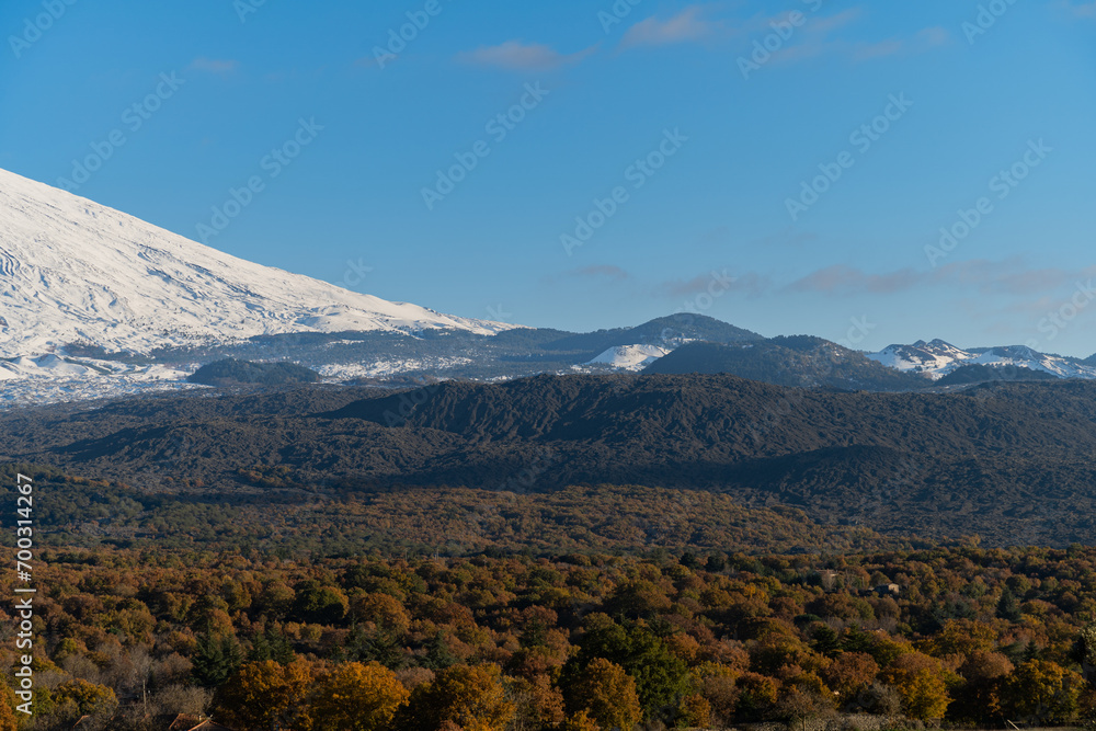 Bronte town under the snowy and majestic volcano Etna and a cloudy blue sky