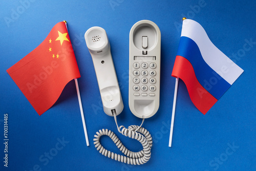 Telephone and two flags on a blue background, concept on the theme of telephone conversations between China and Russia