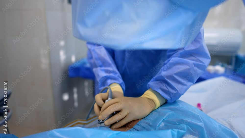 Hands of doctor in latex gloves hold the ultrasound transducer attached to a patient. Surgeon turns around to take a tool and input it into patient's body. Hands of doctor in latex gloves hold the ultrasound transducer attached to a patient. Surgeon turns around to take a tool and input it into patient's body.