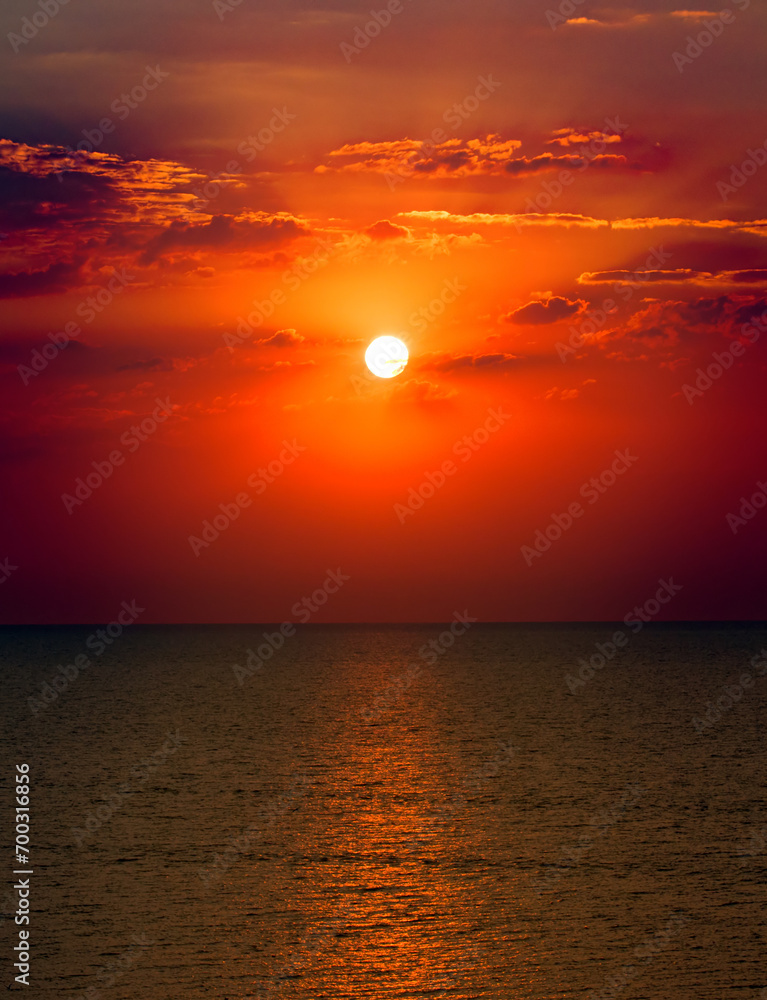 Tropical beach, blue sea and bright sun set. Vertical photo.