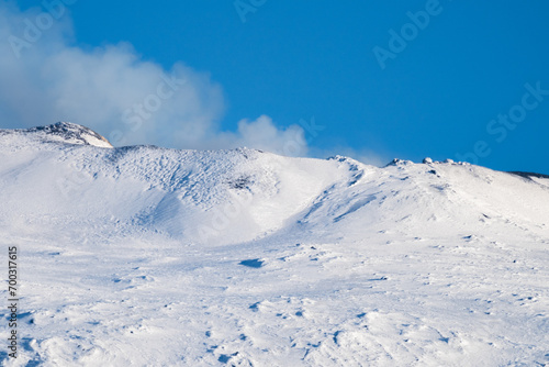 Bronte town under the snowy and majestic volcano Etna and a cloudy blue sky