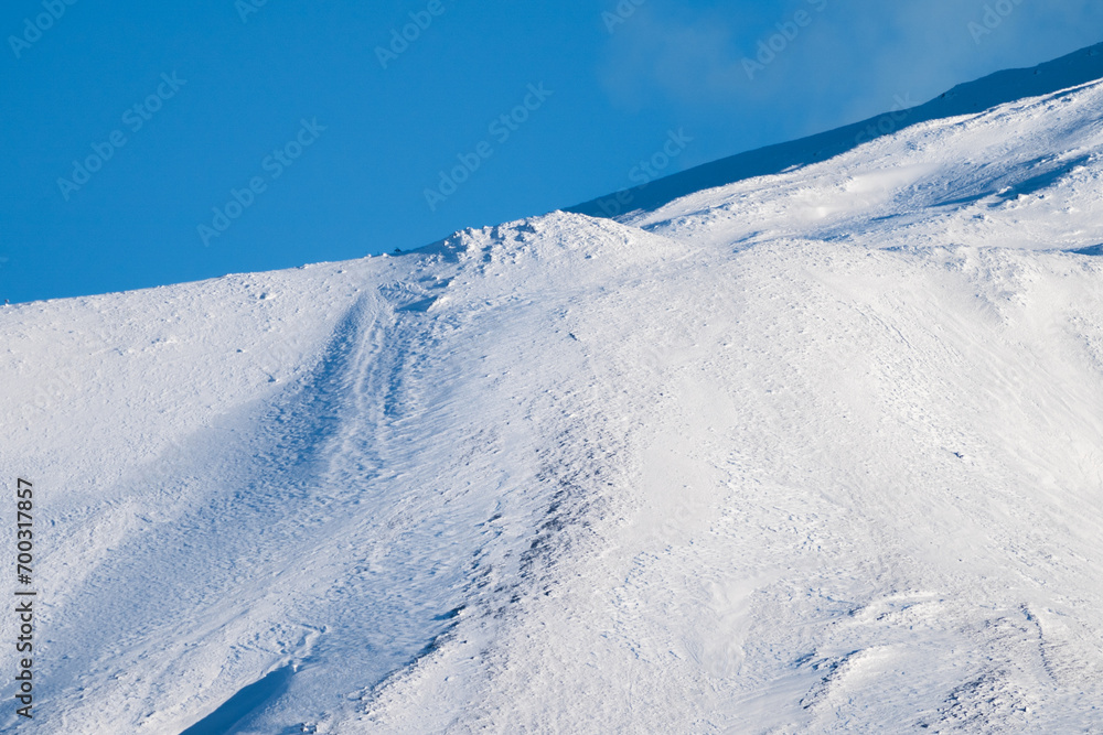 Bronte town under the snowy and majestic volcano Etna and a cloudy blue sky