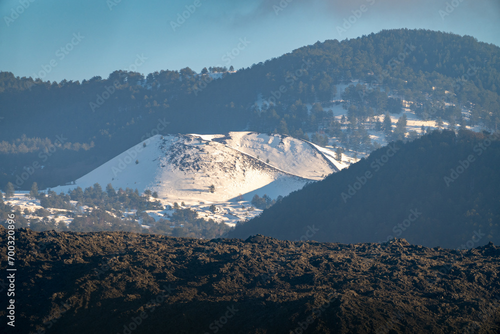 Bronte town under the snowy and majestic volcano Etna and a cloudy blue sky
