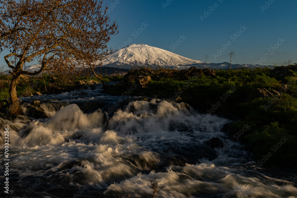 A seasonal river flows under the massive snowcovered Etna volcano. Favare Santa Venera 