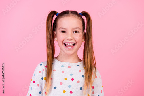 Portrait of funky optimistic schoolgirl with ponytails hairdo dressed dotted sleepwear smiling laugh isolated on pink color background photo