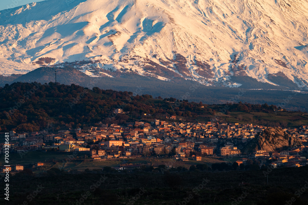 Bronte town under the snowy and majestic volcano Etna and a cloudy blue sky