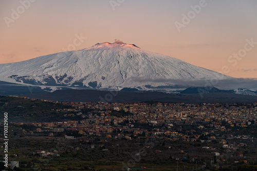 Bronte town under the snowy and majestic volcano Etna and a cloudy blue sky