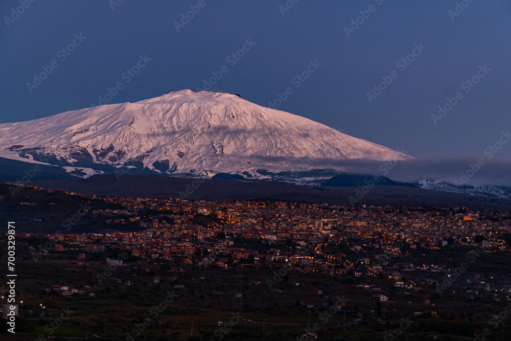 Bronte town under the snowy and majestic volcano Etna and a cloudy blue sky