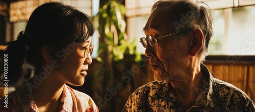 Asian daughter and elderly father enjoying quality time and conversation at home. photo