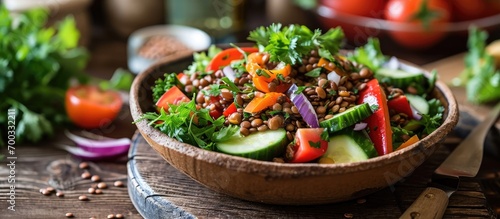 Focus on lentil salad with vegetables and coriander on wooden table.
