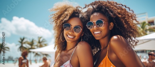 Black women friends in an urban city enjoying a summer vacation in sunny Miami. Happy travel couples or young people smiling near the ocean for vitamin D. © TheWaterMeloonProjec