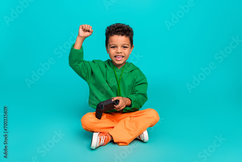 Photo of excited crazy cute boy dressed stylish green clothes raise hands win competition isolated on cyan color background