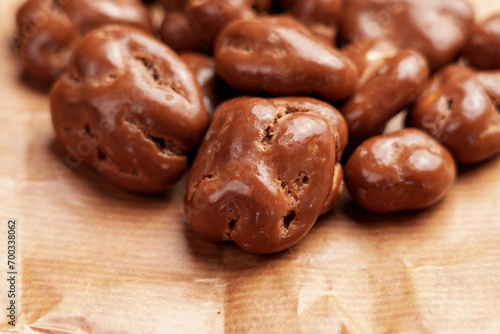 Glazed chocolate nut candy with dried walnuts on a brown package paper.