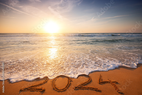 Happy New Year 2024 concept, lettering on the beach. Written text on the sea beach at sunrise. © ValentinValkov