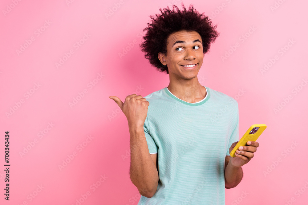 Photo of good mood dreamy guy wear blue t-shirt typing modern device thumb empty space isolated pink color background