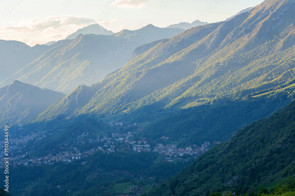 Beautiful landscape of the layered misty hazy Italian Alps mountain range during evening. Alpine summer sunrise. Lombardy, Italy