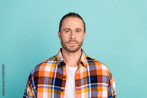 Photo of serious confident brutal man with beard dressed flannel checkered shirt look at camera isolated on turquoise color background