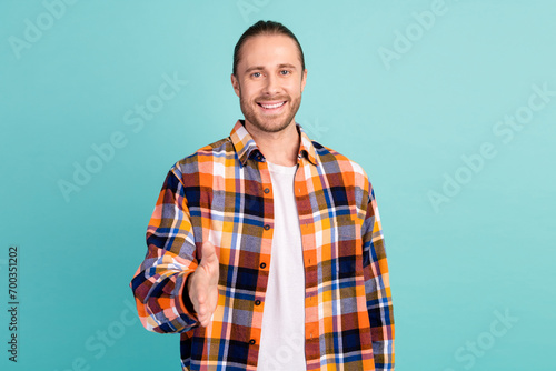 Photo of friendlu cheerful nice man with stubble dressed checkered shirt stretching arm to you greetings isolated on teal color background photo