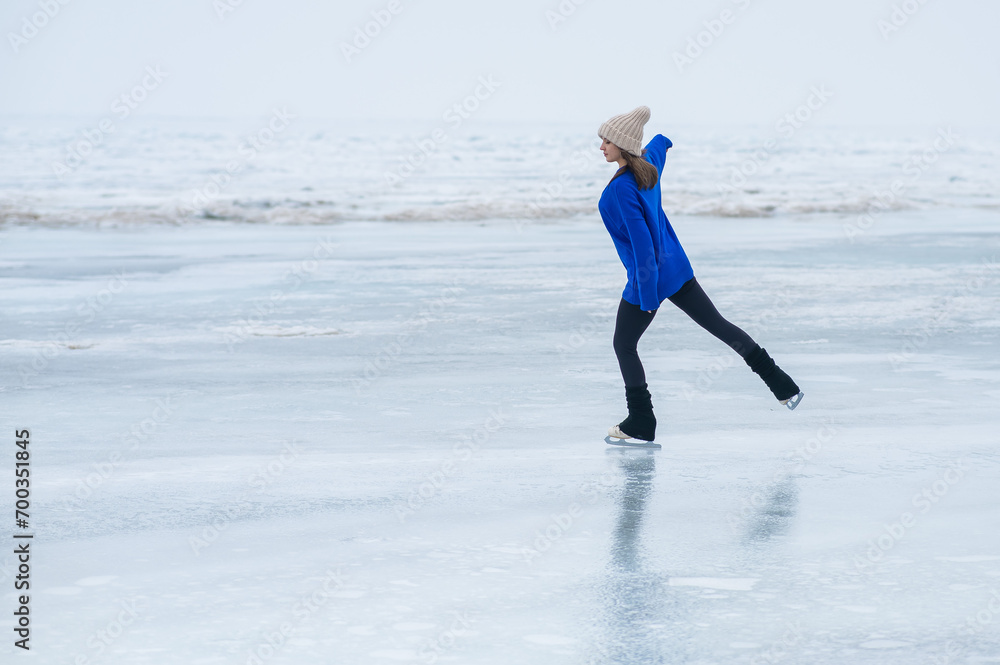 Caucasian woman in a blue sweater is skating on a frozen lake. The figure skater performs the program. Caucasian woman in a blue sweater is skating on a frozen lake. The figure skater performs the program.